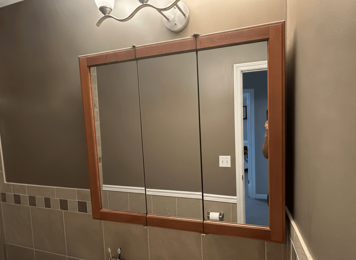 Wood-framed recessed medicine cabinet with three mirrored doors.